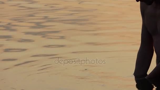 L'homme lève une poignée d'eau dans un lac au coucher du soleil — Video