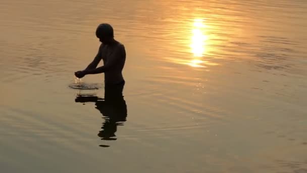 Teenager raises a handful of water in a lake at a sunset in slo-mo — Stock Video