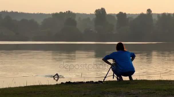 Swimming crawl man and a shooting camera woman at sunset — Stock Video