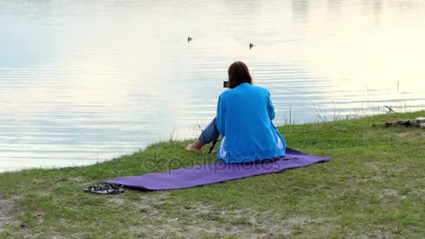 Młoda kobieta strzela kaczki jako operator na brzegu jeziora w slo-mo — Wideo stockowe