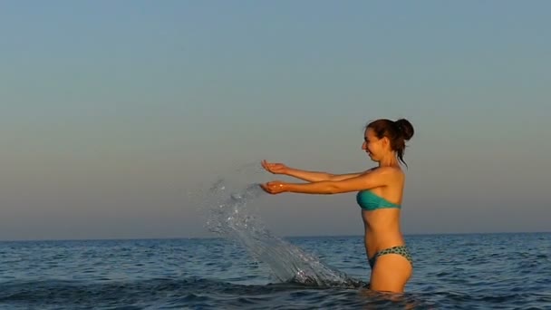 Merry young woman raises her hands and makes splashes in slo-mo — Stock Video