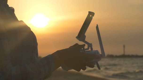 Женские руки управляют пультом управления беспилотником на закате — стоковое видео