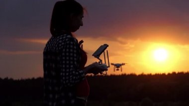Parlak kadın slo-mo gün batımında onun dron çalışmasına bir panel tutar