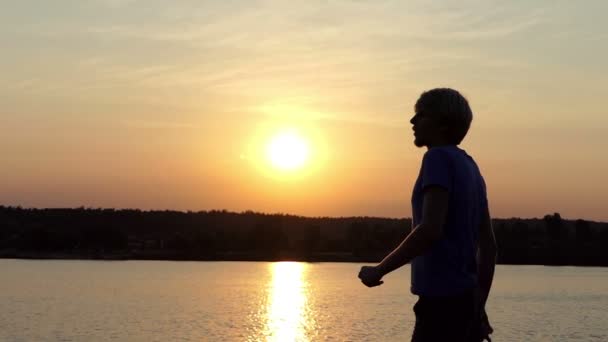 Щасливий чоловік піднімає свою чемпіонську чашу на заході сонця в шлю-мо — стокове відео