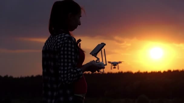 Mujer brillante sostiene un panel para operar su dron al atardecer en slo-mo — Vídeo de stock