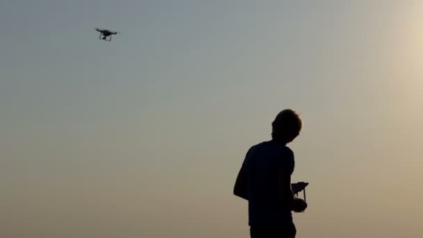 Smart man controls his flying drone with panel at sunset in slo-mo — Stock Video