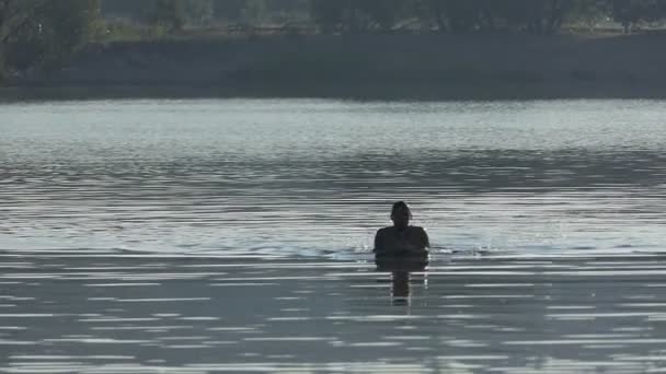 Sportiga mannen simmar bröstsim i en sjö vid solnedgången i slo-mo — Stockvideo