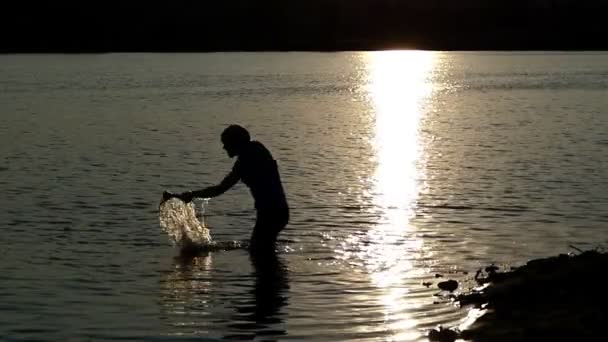 Fiatal férfi húz egy bajnok tál, ki a tó naplementekor a slo-mo — Stock videók