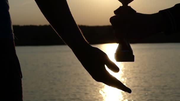 Mano masculina da un tazón ganador a otro al atardecer — Vídeos de Stock