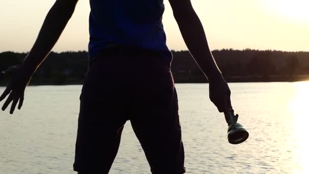 陽気な男スローモーションで夕暮れ時の湖で勝者のボウルを発生させます — ストック動画