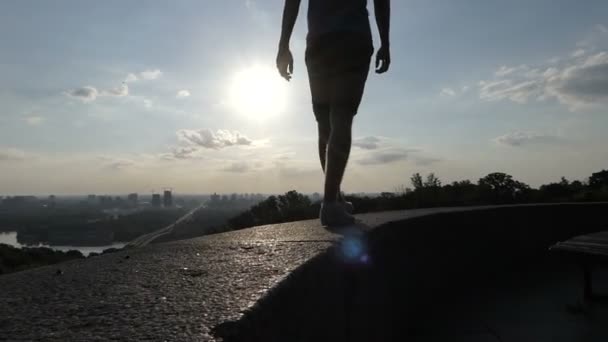 若い男がスローモーションでキエフで堤防壁のカバー プレートの上を歩く — ストック動画