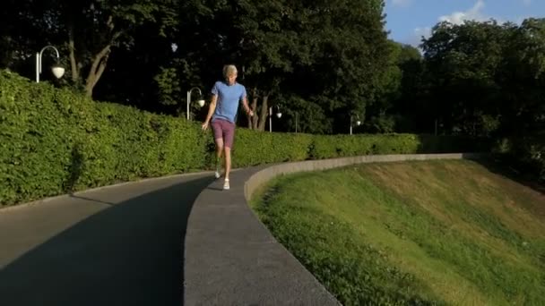 Jeune homme danse sur un trottoir demi rond protégeant parc — Video