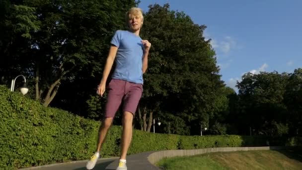 Lycklig man danser på en halv runda trottoarkanten skydda park i slo-mo — Stockvideo