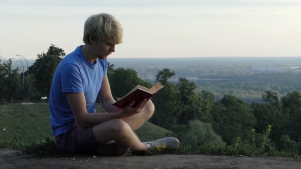 Slimme man leest een boek over een stoeprand van een observatie dek in slo-mo — Stockvideo