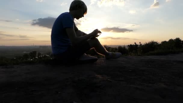 Jonge journalist schrijft een kort verhaal op een gazon bij zonsondergang in slo-mo — Stockvideo