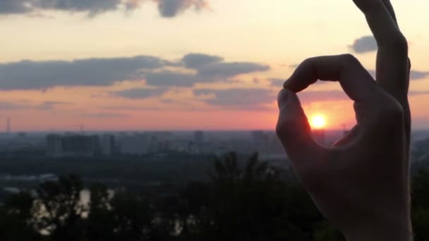 Männliche Hand behält die OK-Geste mit der Sonne darin bei Sonnenuntergang — Stockvideo