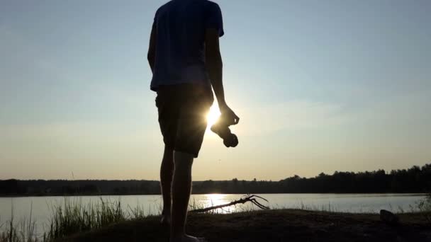 Joven trata de disparar un sendero dorado al atardecer en slo-mo — Vídeo de stock