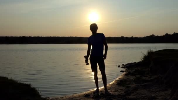 Junger Mann springt mit Meisterschale bei Sonnenuntergang in Slo-mo — Stockvideo