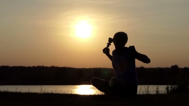 Feliz hombre se sienta en una orilla del lago y levanta su cuenco campeón en slo-mo — Vídeos de Stock