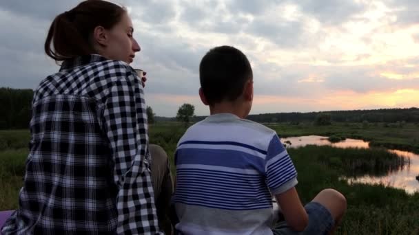 Junge Frau und ein Junge blicken mit ihrer Drohne an einem See in den Himmel — Stockvideo