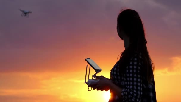 Leende kvinna driver en panel för att styra en drönare i solnedgången — Stockvideo