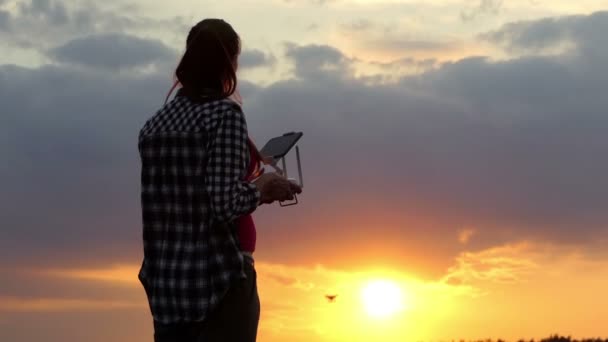 Mujer delgada opera un panel para controlar un dron al atardecer — Vídeo de stock