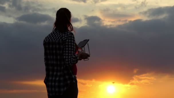 Traumfrau bedient ein Panel zur Steuerung einer Drohne bei Sonnenuntergang — Stockvideo