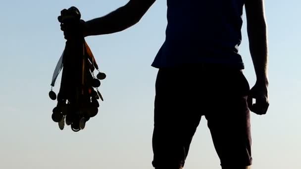Sportieve man houdt een bundel van winnaar medailles bij zonsondergang in slo-mo — Stockvideo