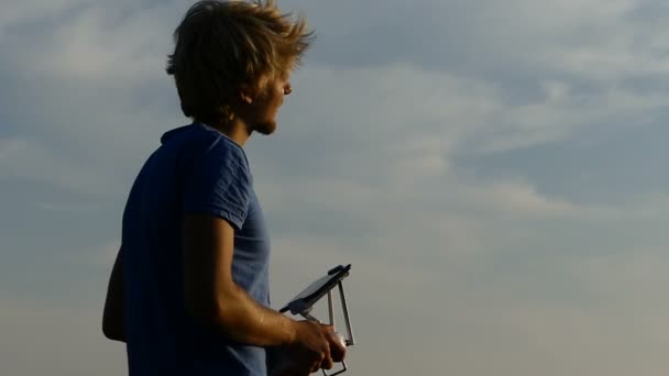 Pro man trabaja con un panel de control de drones al atardecer en slo-mo — Vídeos de Stock