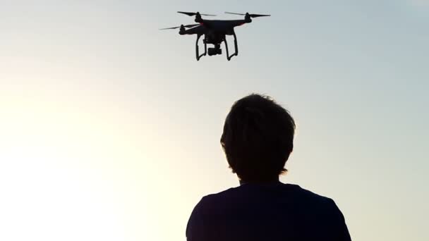 Akıllı adam çekimde panelini kullanarak uçan bir quadracopter kontrol eder. — Stok video
