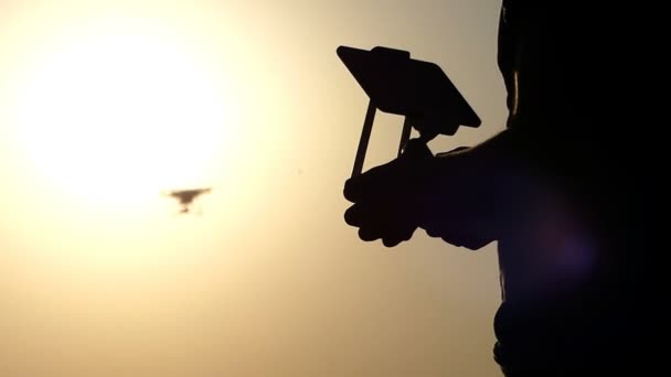 Um close-up de mãos masculinas, painel de controle, e um drone voador ao pôr do sol — Vídeo de Stock