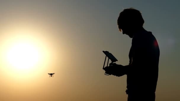 El hombre inteligente dirige el vuelo de un dron a una puesta de sol dorada en slo-mo — Vídeos de Stock