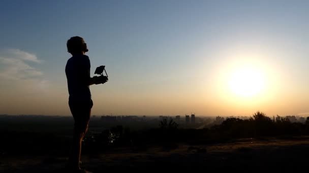 Pro ember irányítja a repülés egy drone egy napnyugtakor a slo-mo — Stock videók