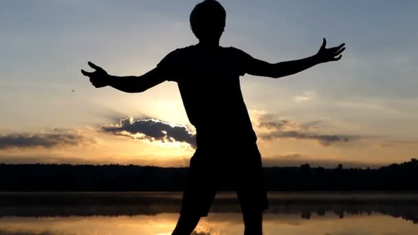 Homem hilariante dança discoteca em um banco de lago ao pôr do sol — Vídeo de Stock