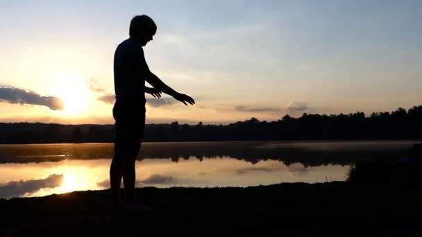 Jovem está de pé em suas mãos e caminha ao pôr do sol — Vídeo de Stock