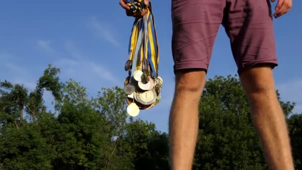 Jovem levanta um pacote de medalhas em um banco de lago no verão — Vídeo de Stock