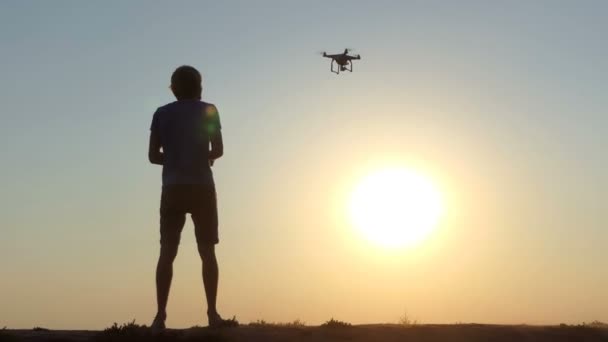 Cameraman opera o voo de um drone voador ao pôr do sol em slo-mo — Vídeo de Stock