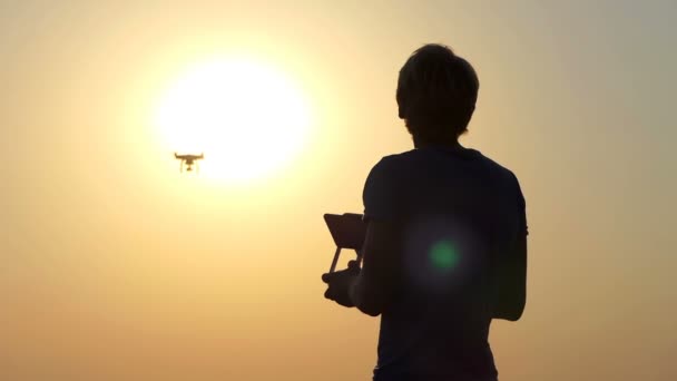 Cameraman loiro usa um quadricóptero voador ao pôr do sol em slo-mo — Vídeo de Stock