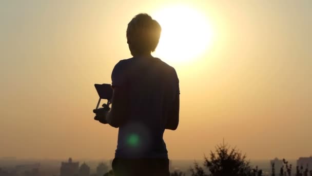 幸運な男は、スローモーションで夕暮れ時新しい飛行 quadracopter を使用します。 — ストック動画