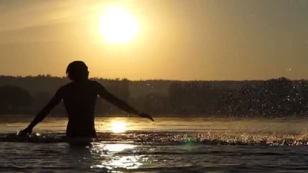 Komik adam slo-mo gün batımında eğlendirmek için göl su atıyor — Stok video