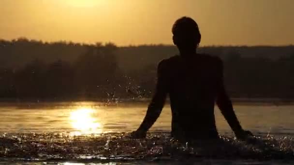 Homem engraçado levanta a água do lago para entreter ao pôr do sol em slo-mo — Vídeo de Stock