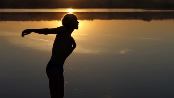 Un uomo energico agita le mani su una riva del lago. Nuoterà. . — Video Stock