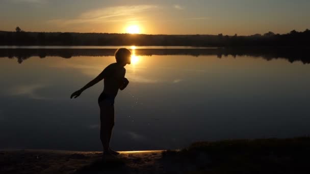 El hombre rubio pone sus manos en una orilla del lago. Planea nadar. . — Vídeos de Stock