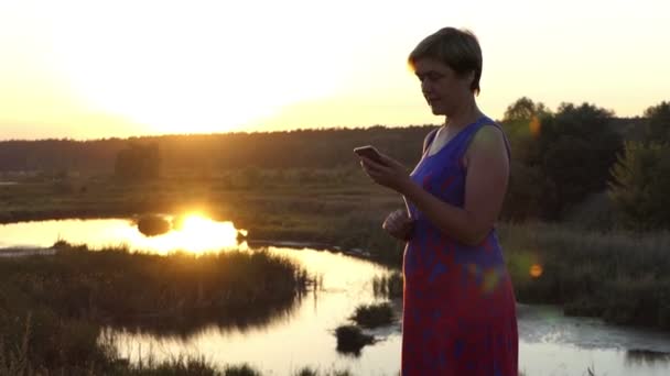 Krásná žena hovory na nádherný západ slunce v létě — Stock video