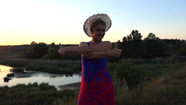 Vrolijke vrouw dansen op de oever van een meer bij zonsondergang — Stockvideo