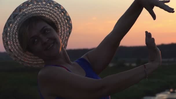 Mujer optimista baila en una orilla del lago al atardecer en slo-mo — Vídeo de stock