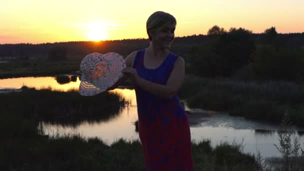 Mujer feliz baila con un sombrero de paja al atardecer — Vídeos de Stock