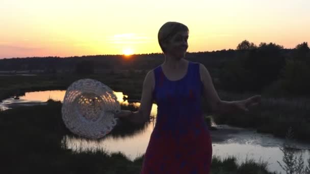 Mulher inteligente dança com um chapéu de palha ao pôr do sol — Vídeo de Stock