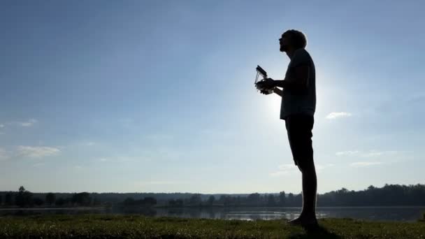 Pro man mira su panel y opera un dron al atardecer en slo-mo — Vídeos de Stock