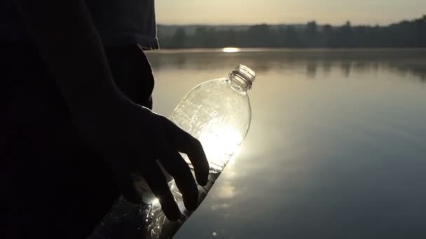 Mladý muž vyvolává plastové láhve pít vodu při západu slunce v slo-mo — Stock video